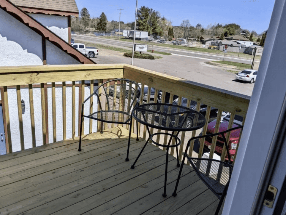Wooden balcony with a small table and chairs overlooking the street