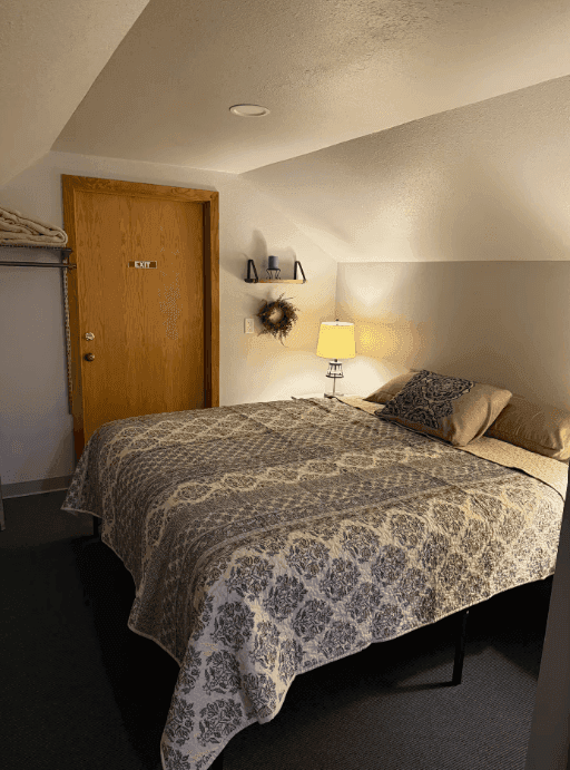 Bed and bedside lamp beneath the apartment's sloping ceiling