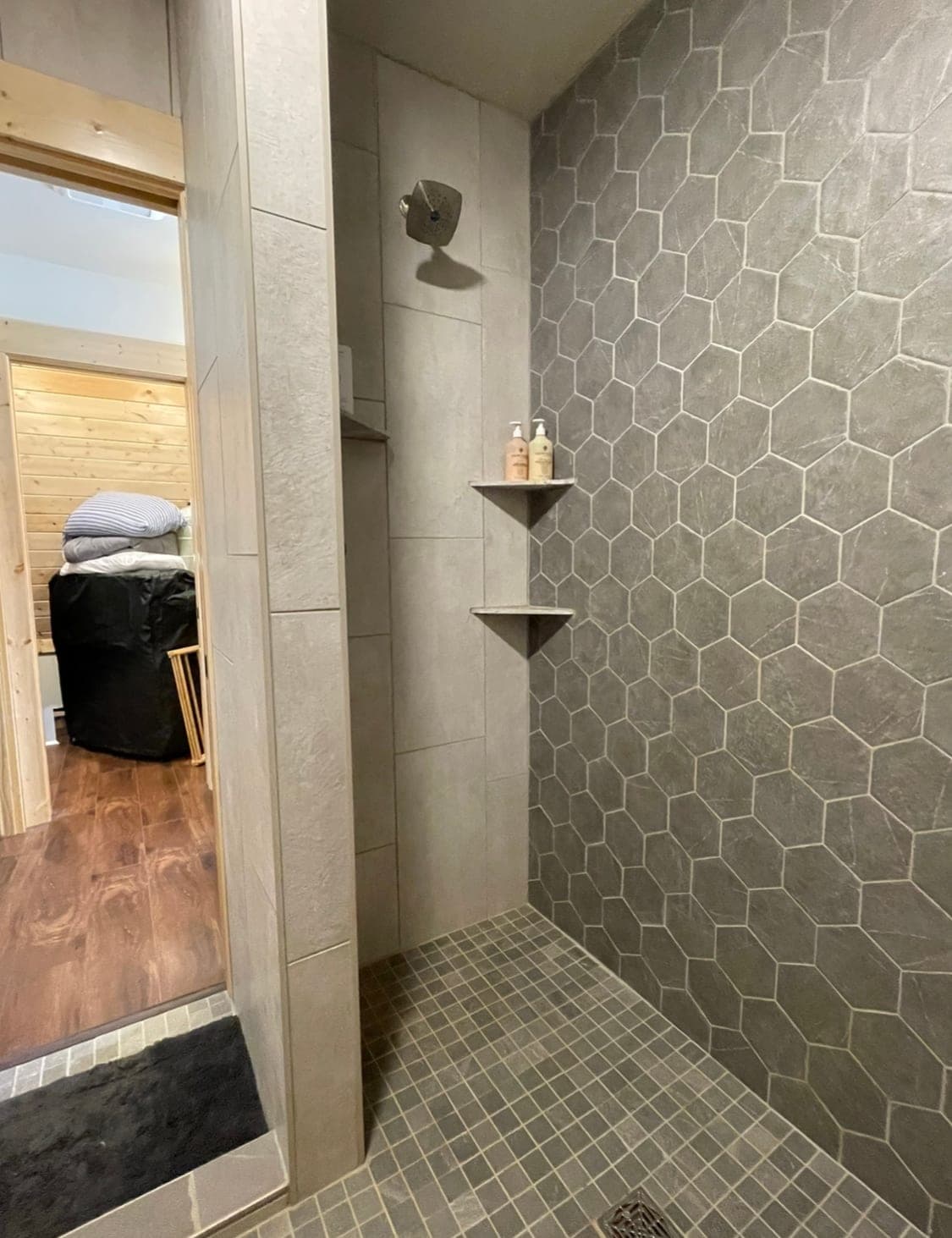 Shower entrance with patterned tile wall and recessed shelf