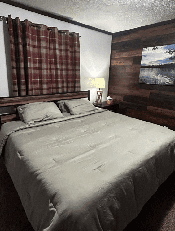 Bedroom with gray bedding, plaid curtains and a wood accent wall