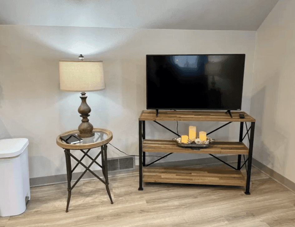 Television on a metal-framed stand beside a table lamp