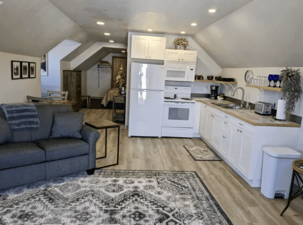Open apartment living area with sofa and white kitchen cabinets