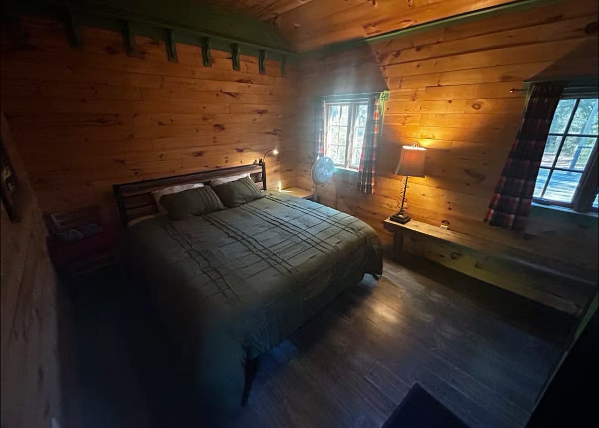Wood-paneled bedroom with plaid curtains and a bedside lamp